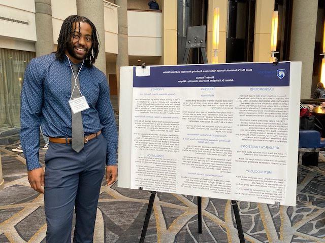 PSS major student standing in front of poster board project 